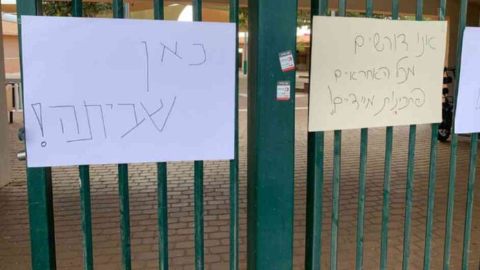 בתמונה, שלט על גדר בית ספר הנושא את המילים כאן שביתה. צילום שי בראון, יו