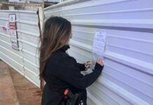 צו סגירה מינהלי לשני אתרי בנייה בנתניה שהעסיקו שוהים בלתי חוקיים שוטרת מצמידה צו סגירה זמני לאתר בנייה בנתניה. צילום משטרת נתניה