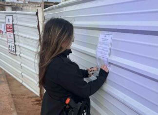 צו סגירה מינהלי לשני אתרי בנייה בנתניה שהעסיקו שוהים בלתי חוקיים שוטרת מצמידה צו סגירה זמני לאתר בנייה בנתניה. צילום משטרת נתניה